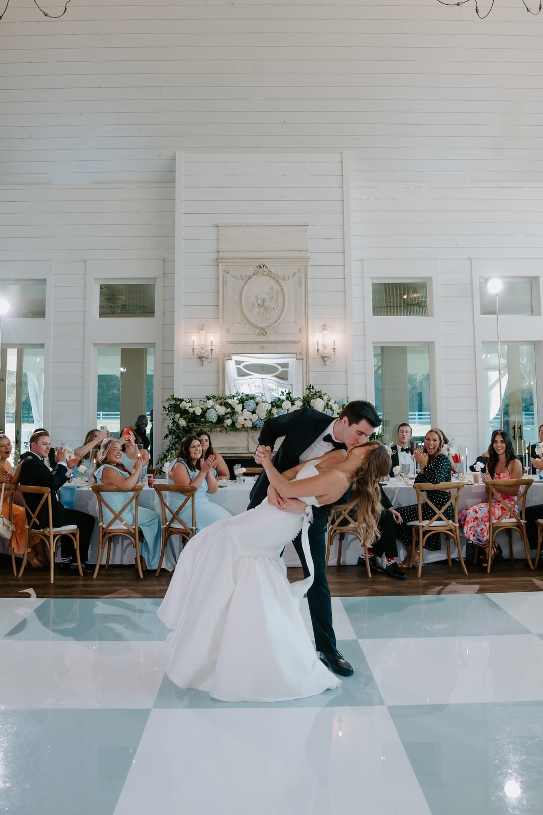 First-dance dip on the checkered floor with guests watching from the tables