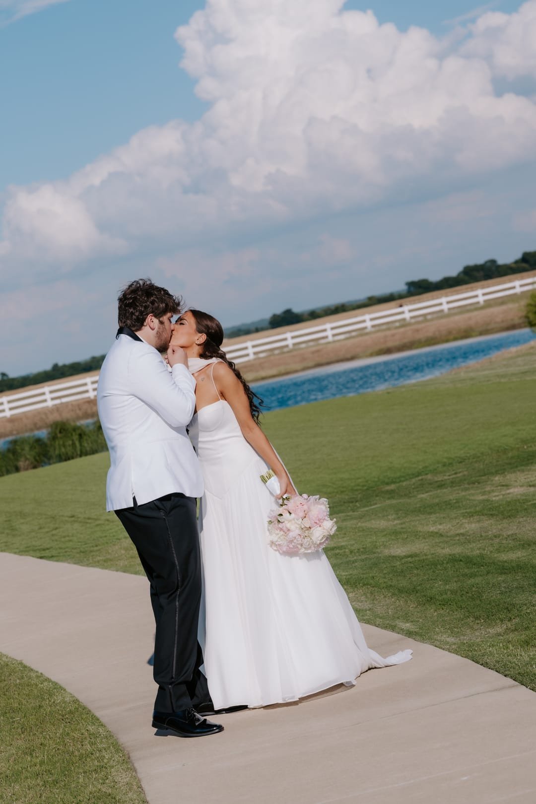 Kiss on the path beside the pond under a tall bank of summer cloud